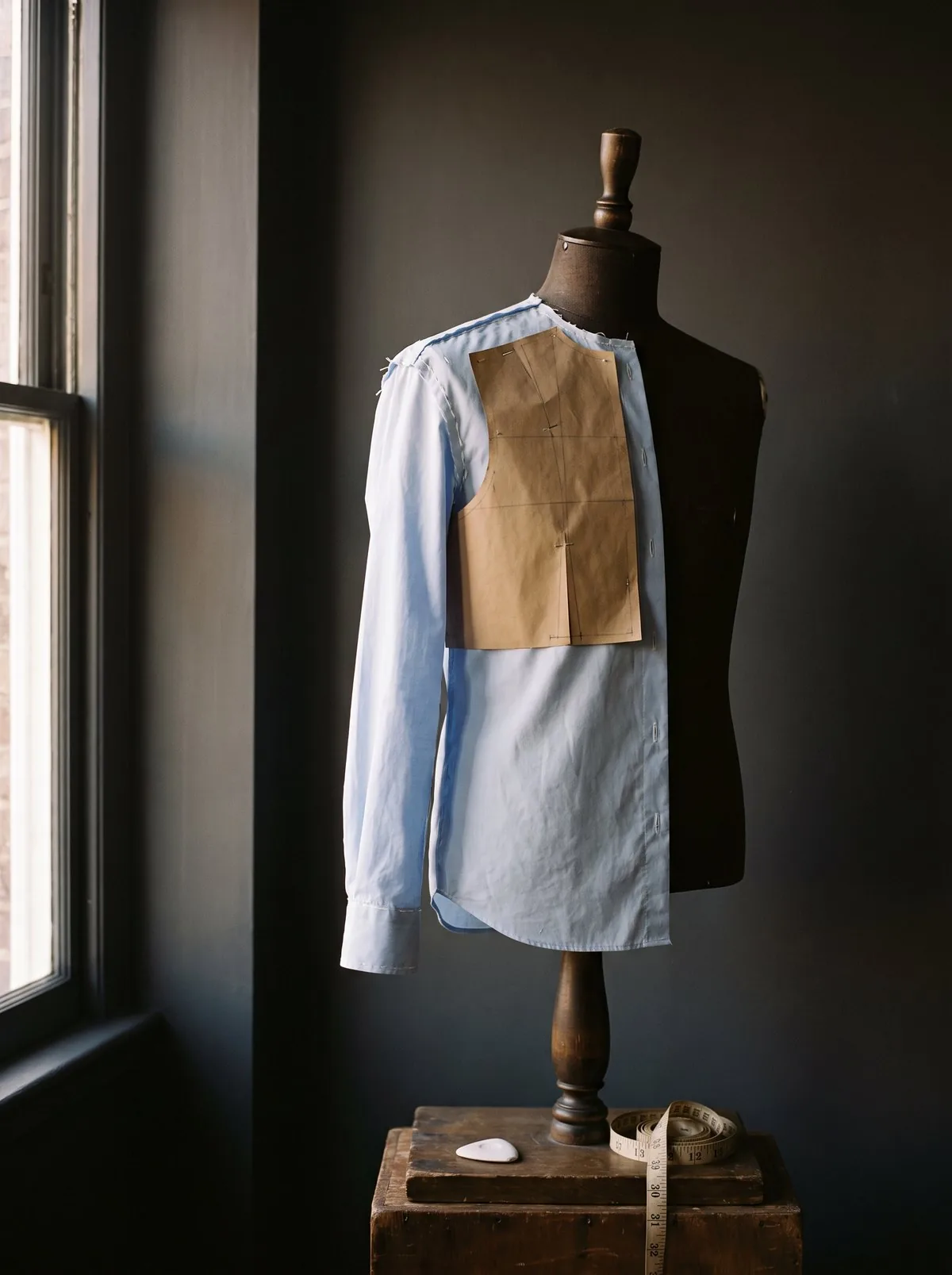 A half-made shirt on a tailor's dress form, the paper pattern still pinned to it