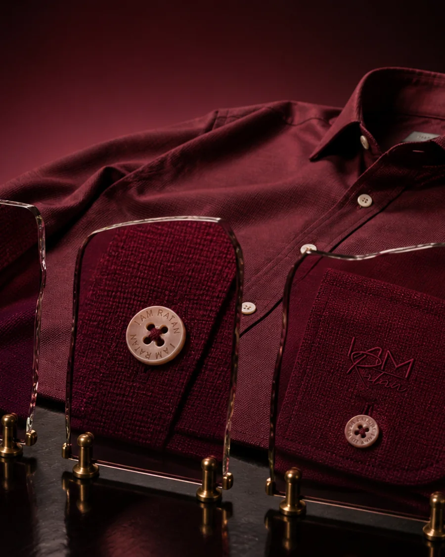 A claret shirt with cloth swatches and engraved buttons set before it